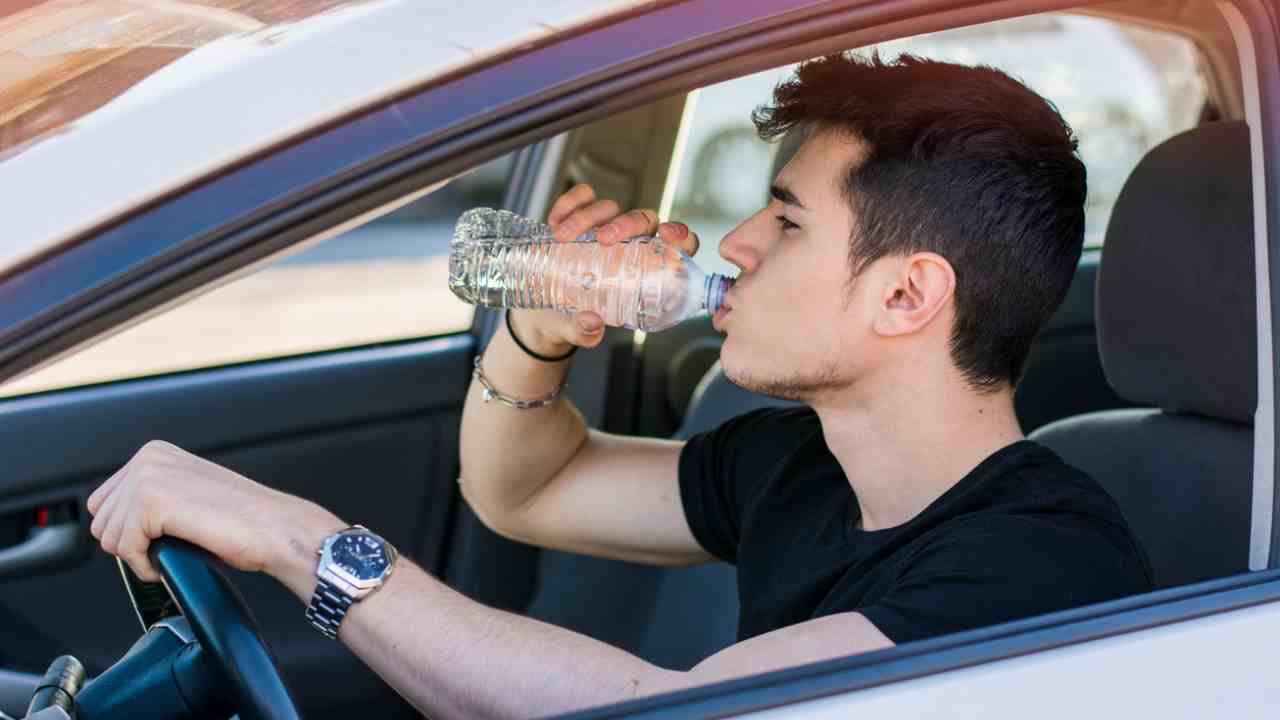 Ragazzo che beve acqua in auto