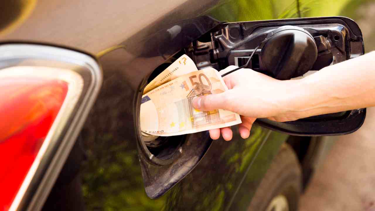 Un signore infila i soldi nel boccaporto della benzina